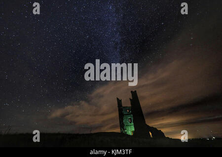 Lilburn Tower, parte delle rovine del castello di Dunstanburgh ad Alnwick, Northumberland, sotto un cielo stellato. Foto Stock