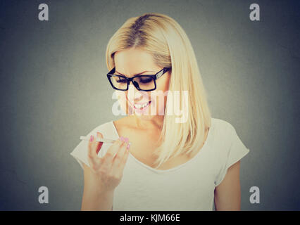 Donna che indossa occhiali che usano un telefono intelligente funzione riconoscimento vocale online isolato sul muro grigio sfondo