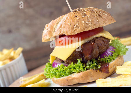 Cheeseburger con carne di manzo e patatine fritte sul tavolo di legno Foto Stock
