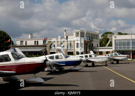 Fila di luce-aeromobile Piper Cherokees e un faggio Bonanza parcheggiato sul piazzale con terminal dietro Foto Stock