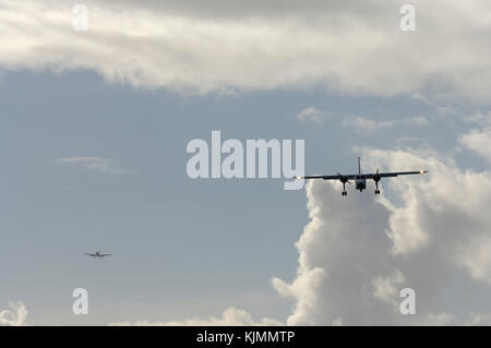 BN Islander sul finale-approccio con un Airbus A310 aereo di linea e di Cumulus nuvole dietro Foto Stock