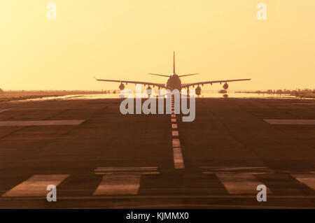 Un aereo jet rullaggio al tramonto sulla pista di Sint Maarten nelle Antille Olandesi. Foto Stock