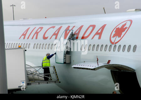 Uomini che indossano il giallo ad alta viz tabard catering di caricamento in un Air Canada Airbus A340-300 parcheggiato sul terminale 3 Foto Stock