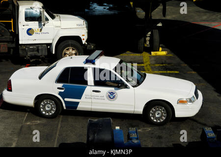 US Customs and Border Protection auto con un LSG Sky Chef catering carrello e il sottocarro nosewheel di un American Airlines Airbus A300-600R parke Foto Stock