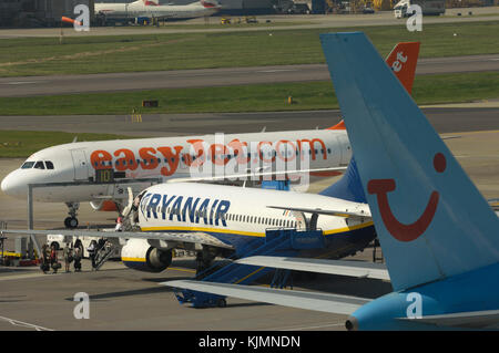 Coda di una Thomsonfly.com Boeing 767-304 ER, un Ryanair 737-800 con Servisair airstairs parcheggiato sul piazzale e un easyJet Airbus A319-100 dietro Foto Stock