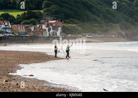 Due uomini che pescano sulla spiaggia di Sandsend, whitby, regno unito Foto Stock