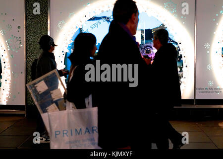 Shoppers passano davanti a John Lewis display di Natale su Oxford Street, London, Regno Unito Foto Stock