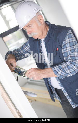 Artigiano tenendo un cacciavite e una presa elettrica Foto Stock