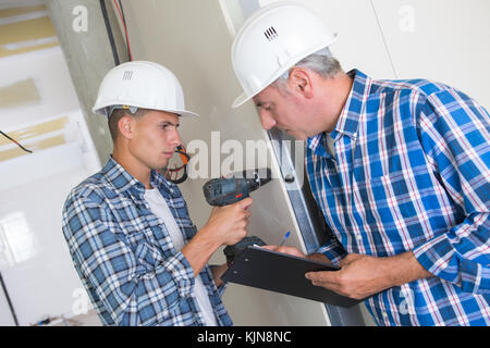 Carpentiere e aiutante di insieme di perforazione Foto Stock