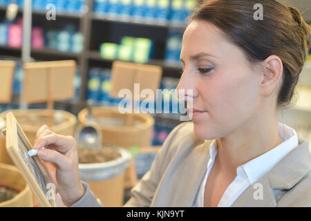 Personale femminile writting a bordo nel supermercato Foto Stock