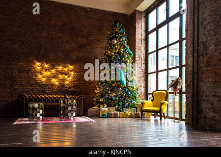 Dark Room con Natale e Anno nuovo arredamento. albero verde decorato con giocattoli e ghirlanda lampeggiante giallo e sedia. lampade illuminate su Foto Stock