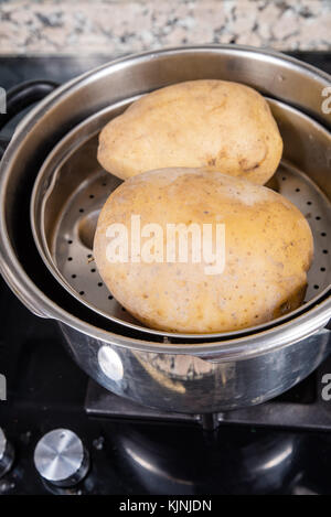 Tutto il vapore patate bollite in una pentola a pressione Foto Stock