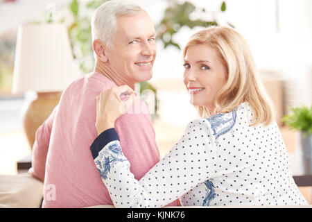 Vista posteriore del colpo di una felice coppia senior seduti sul divano e guardando indietro. Foto Stock