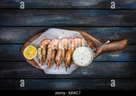 Grandi Rossi di gamberi argentina o langoustine con salsa bianca e la metà di un limone su una tavola di legno. vista superiore Foto Stock