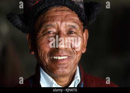 Ladakhi uomo in abiti tradizionali all'interno di casa sua, Leh, Ladakh, Jammu e Kashmir in India. Foto Stock