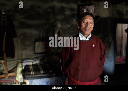 Ladakhi uomo in abiti tradizionali all'interno di casa sua, Leh, Ladakh, Jammu e Kashmir in India. Foto Stock