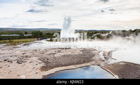 Viaggio in Islanda - la gente vicino strokkur geyser eruzione e pool di geysir in area haukadalur in autunno Foto Stock