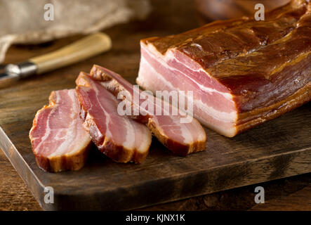 Deliziosa tutta artigianale affumicata pancetta lastra su un blocco di taglio. Foto Stock