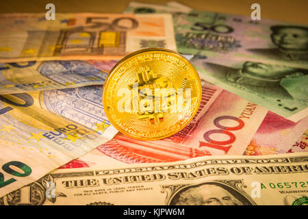 Golden bitcoin moneta oltre il dollaro, euro e yuan fatture. concetto finanziario. situazione di bitcoin e altri cryptocurrencies nel mondo reale Foto Stock