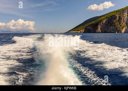 Sentiero dell'acqua la formazione di schiuma dietro un battello da crociera. costa dell'isola di Zante in background. Grecia. Foto Stock