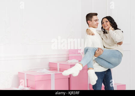 Paio di adolescenti in piedi accanto ai doni. egli detiene la sua ragazza nelle sue braccia. vacanze. Felice anno nuovo. Buon Natale. il giorno di San Valentino. nascita Foto Stock