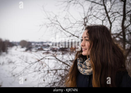 Malinconici e ragazza romantica con bellissimi capelli lunghi sullo sfondo inverno guardando lontano sul paesaggio invernale Foto Stock