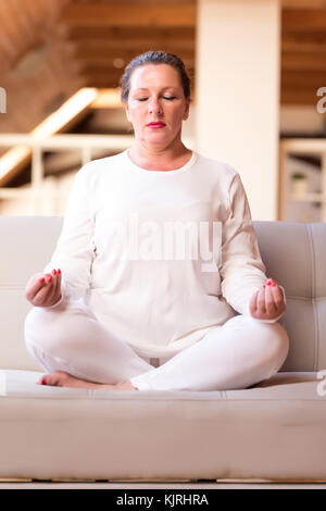 Ritratto di una donna di mezza età meditando nel suo appartamento in mansarda. Foto Stock