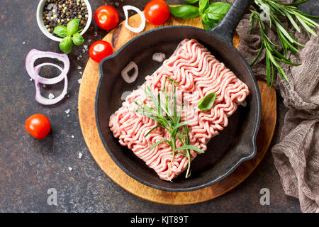 Materie la carne macinata in una ghisa padella, e una varietà di spezie, le verdure e le erbe aromatiche. Foto Stock