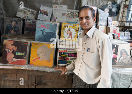 L uomo sta accanto alla sua seconda mano LP in vinile di stallo record nel centro di Mumbai Foto Stock