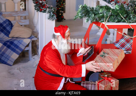 Babbo Natale fa di pollice fino a lavorare con il computer portatile e la bambina Foto Stock