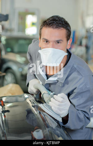 Giovanissimo meccanico la lucidatura di un tipo di carrozzeria Foto Stock