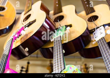 Molti classici in legno colorato chitarre appeso alla parete del negozio showroom, la configurazione di sfondo in Istanbul grand bazaar Foto Stock