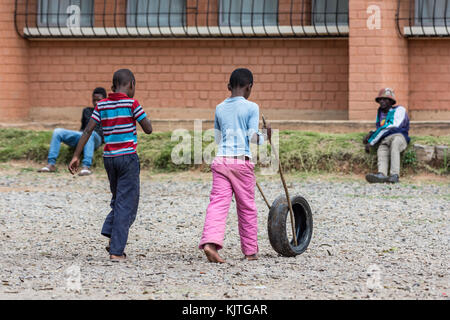 Due ragazzi malgasci giocare di rotolamento dei pneumatici in gomma con due bastoncini. madagascar, africa. Foto Stock