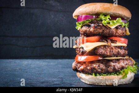 Triple american burger con formaggio e cipolle alla griglia,fuoco selettivo e uno spazio vuoto Foto Stock