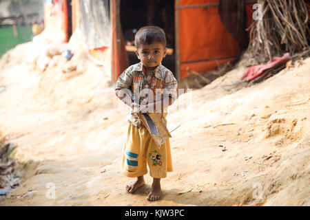 25 novembre 2017 - Cox's Bazar, Bangladesh - Un ragazzo tiene un machete vicino a un rifugio nel campo profughi di Kutupalong. Kutupalong Refugee Camp è un campo profughi situato a Ukhia, nella regione di Cox's Bazar in Bangladesh, che fornisce principalmente frammenti ai musulmani Rohingya fuggiti dalle persecuzioni religiose in Myanmar. L'UNHCR ha stimato che ci sono almeno 30.000 rifugiati nel campo alla fine del 2017. Crediti: Marcus Valance/SOPA/ZUMA Wire/Alamy Live News Foto Stock