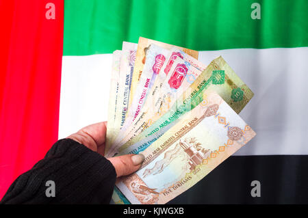 Mano azienda Emirati Arabi Uniti dirhams sulla parte superiore della bandiera Foto Stock