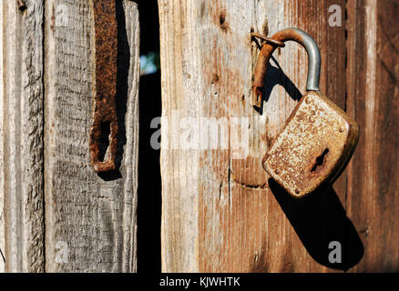 Il fienile bloccare pende sulla vecchia porta di legno. Foto Stock