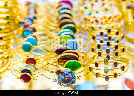 Molti braccialetti dorati di forma e colore diversi con pietre preziose e oro in mostra in vendita nel Grand Bazaar, Istanbul, Turchia Foto Stock