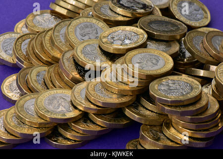 Un mucchio disordinato di lotti di una libbra di monete su un viola malva o sfondo. Monete del Regno e cambio nuovo una libbra di monete vengono salvati nelle banche. Foto Stock