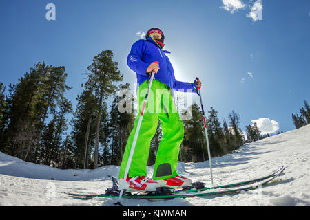 Giovane uomo su sci alpino sorge su una pista innevata contro il cielo. Foto Stock