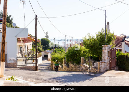 La strada è in discesa attraverso il villaggio al paesaggio collinare a riva. Foto Stock