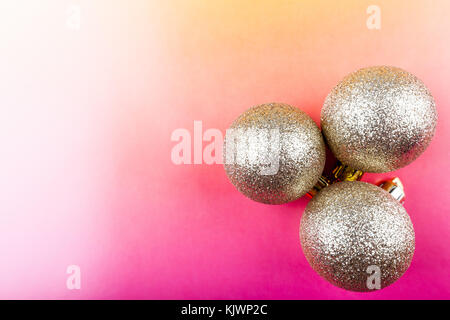 Decorazione di natale, tre golden baubles su uno sfondo colorato. Foto Stock