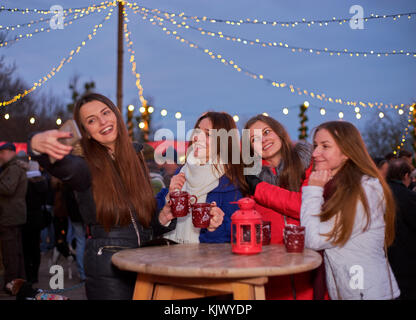 Quattro giovani donna fare foto al mercato di natale Foto Stock