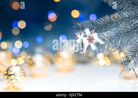 Albero di natale decorazioni sul ramo di argento contro sfondo sfocato con luci delle vacanze Foto Stock