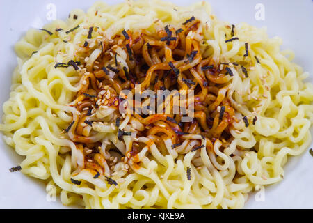 Tagliatelle istante,spaghetti secchi con salsa nel recipiente dello sfondo. Foto Stock