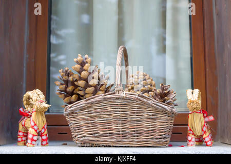 Cestino con pigne nella finestra stagione invernale, Anno Nuovo e le decorazioni di Natale in cesto tessuto con pigne sfondo. Foto Stock