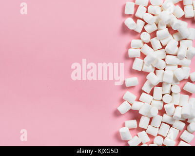 Marshmallows su sfondo rosa con copyspace. Appartamento laici o vista dall'alto. Lo sfondo o la texture di coloratissimi mini marshmallows. Inverno sfondo alimentare conc Foto Stock