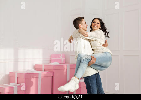 Paio di adolescenti in piedi accanto ai doni. egli detiene la sua ragazza nelle sue braccia. vacanze. Felice anno nuovo. Buon Natale. il giorno di San Valentino. nascita Foto Stock