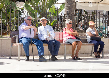 Gli anziani seduto su una panchina pubblica, Sitges, Catalogna, Spagna Foto Stock