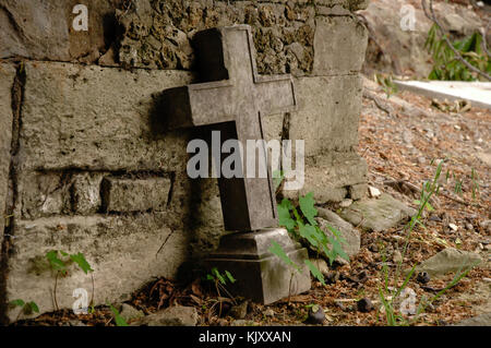 Croce di pietra in piedi contro la tomba al cimitero di Père Lachaise, Parigi, Francia Foto Stock